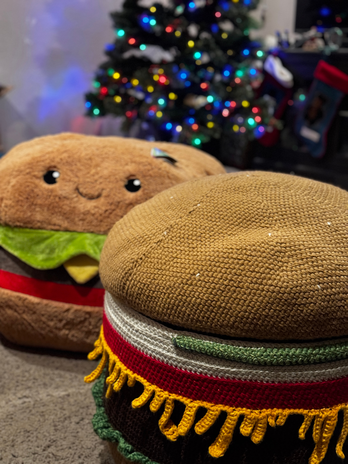 The burger ottoman at home in a living room beside a soft burger pillow.