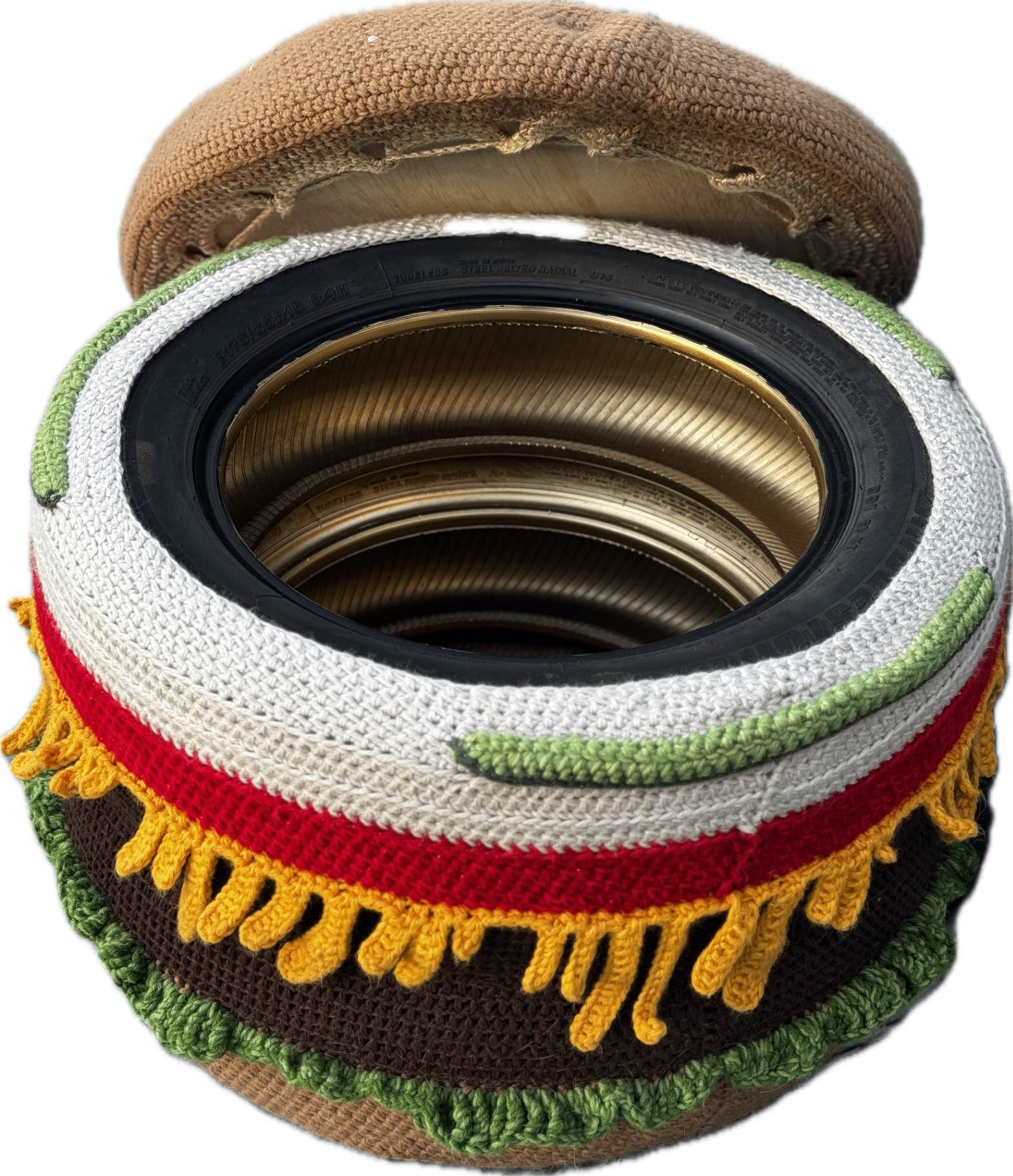 The burger ottoman with its top bun lifted off, showing the open storage space and the 2 upcycled tires that form its base.